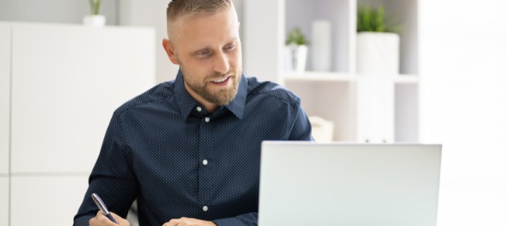 a person using a laptop and taking notes