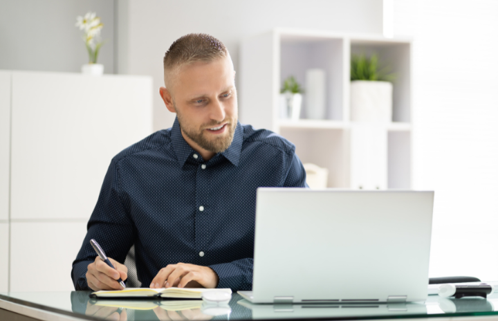 a person using a laptop and taking notes