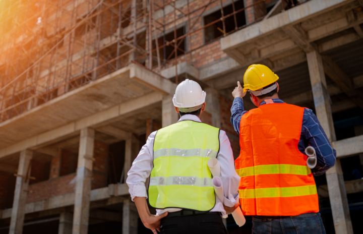 2 construction workers looking at a building and talking