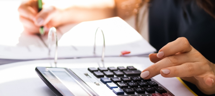 A lady using a calculator and taking notes