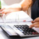 A lady using a calculator and taking notes