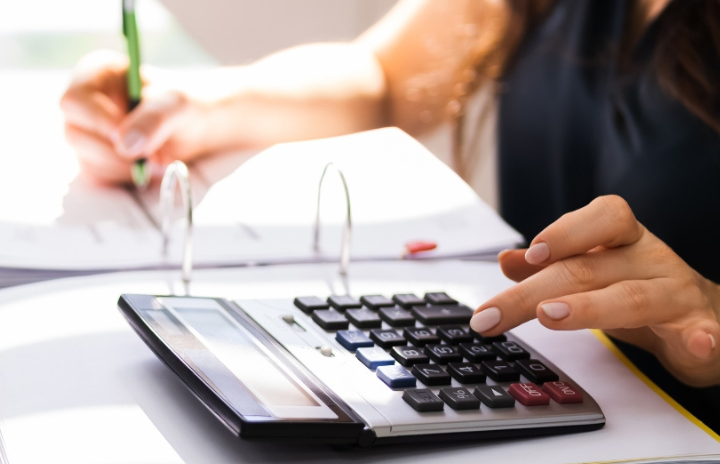 A lady using a calculator and taking notes